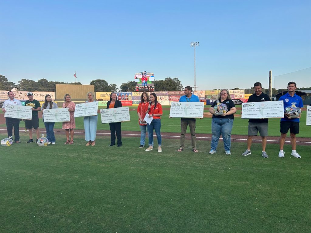 first financial employees presenting gift baskets and checks to delmarva school systems and their teachers of the year on a baseball field